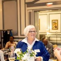 Three event attendees standing together around event table and chatting